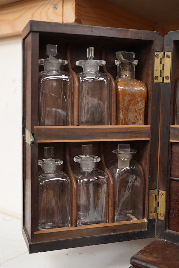 A 19th century mahogany apothecary cabinet, interior with fitting compartments containing twenty-one glass bottles, most with stoppers, five drawers with ivory knobs containing a miniature pestle and water, mixing glasse